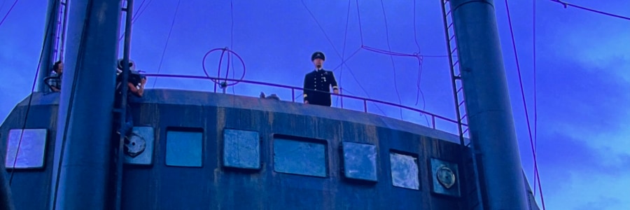 A captain looking down from the bridge at the camera below.