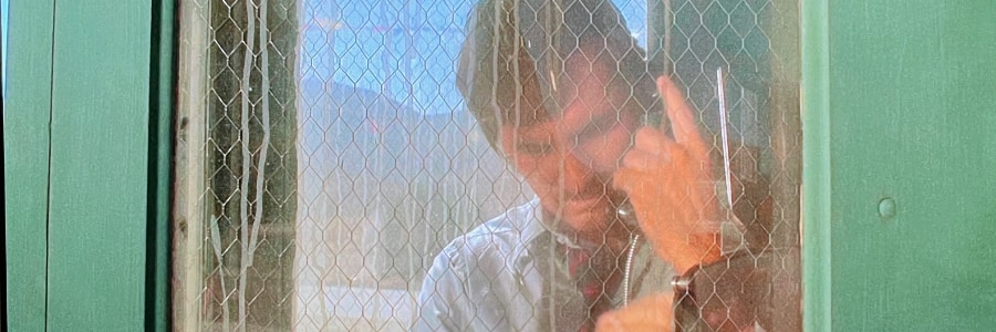 A man in a dusty phone booth making a call.
