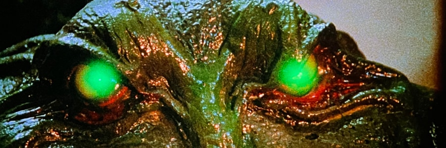 Green slimy alien with glowing green eyes.