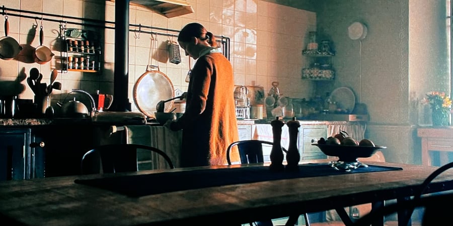 A woman is doing the dishes in a dark kitchen.