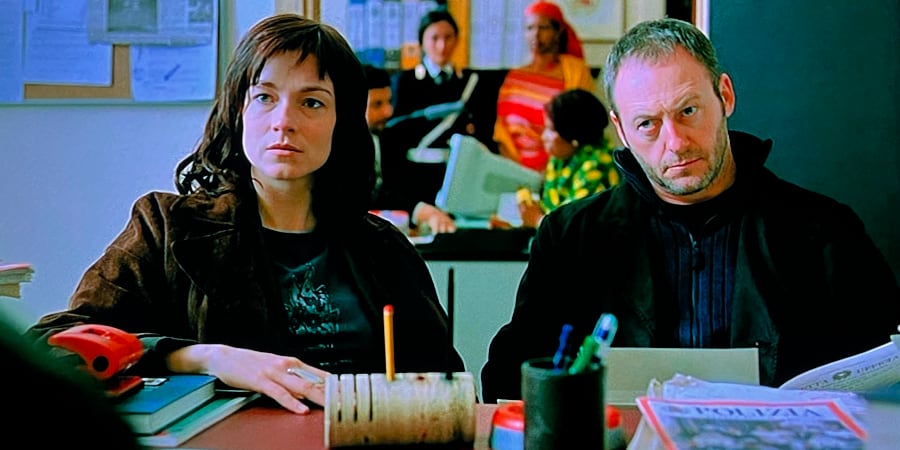 Detective Mari and rogue cop Brannan sit together at a desk.