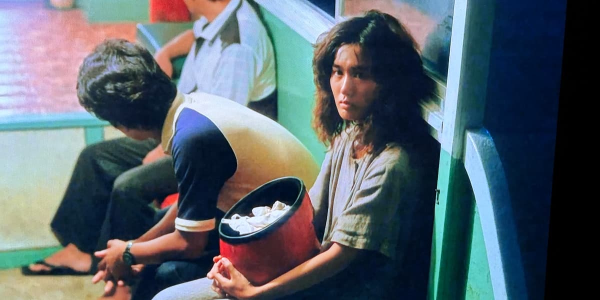 A woman on a boat looks ambiguously at the camera as it pulls out onto the water.