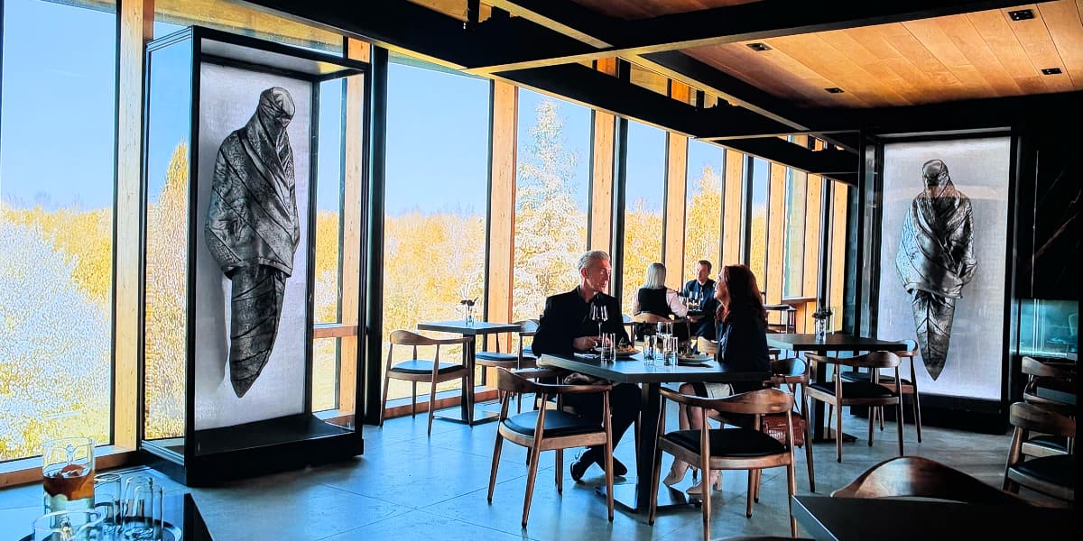 Two people eating in a modern restaurant with two spooky grey shrouds looming over them.