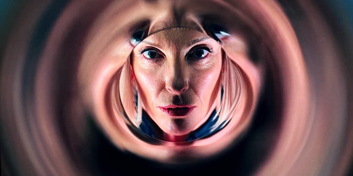 A focussed gallery owner looks into a reflective sculpture.