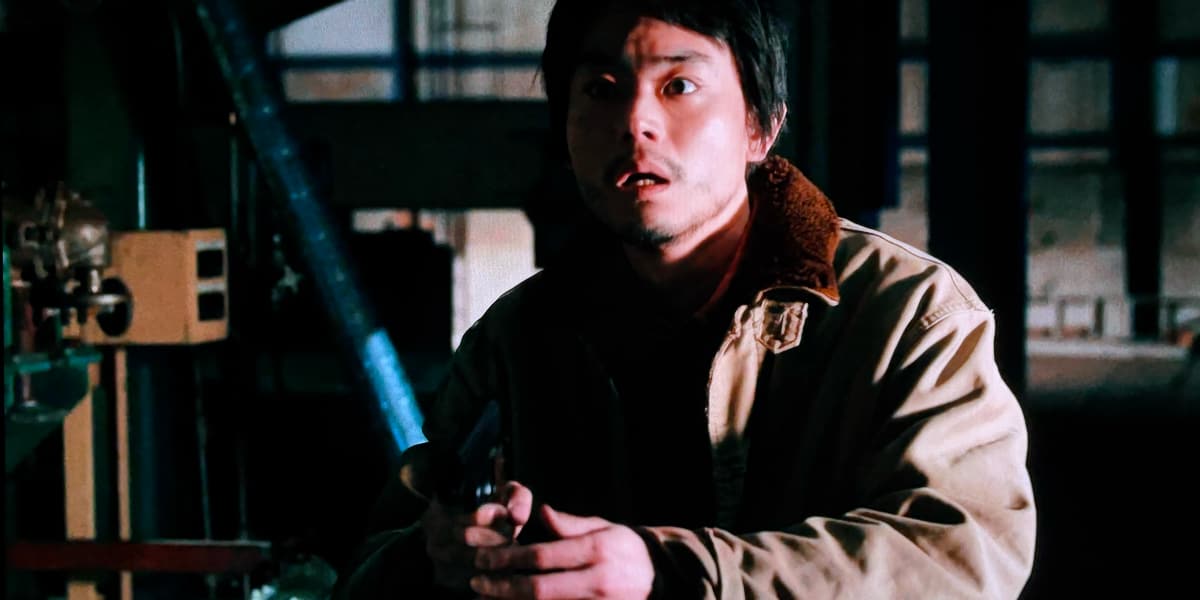 A man holding a gun looks terrified into the darkness ahead.