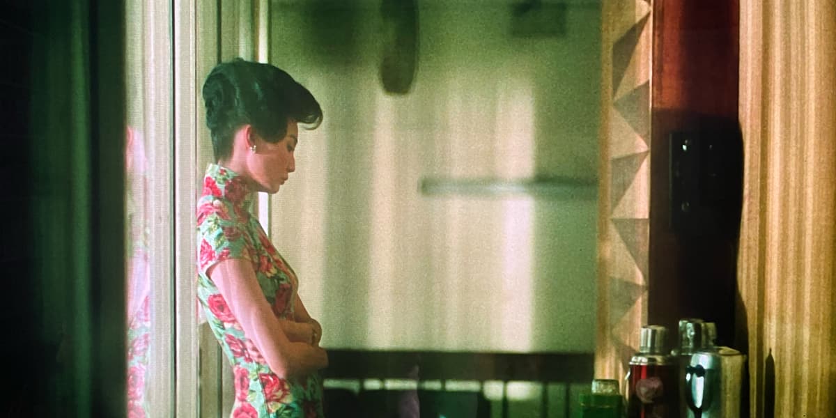 A woman in a beautiful dress stares sadly at a wall.