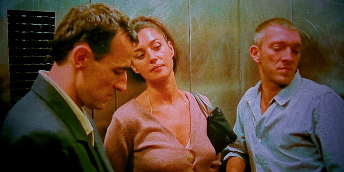 Two men and a woman talk in a lift.