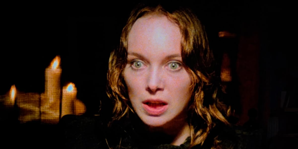 A woman’s frightened face against a black background.