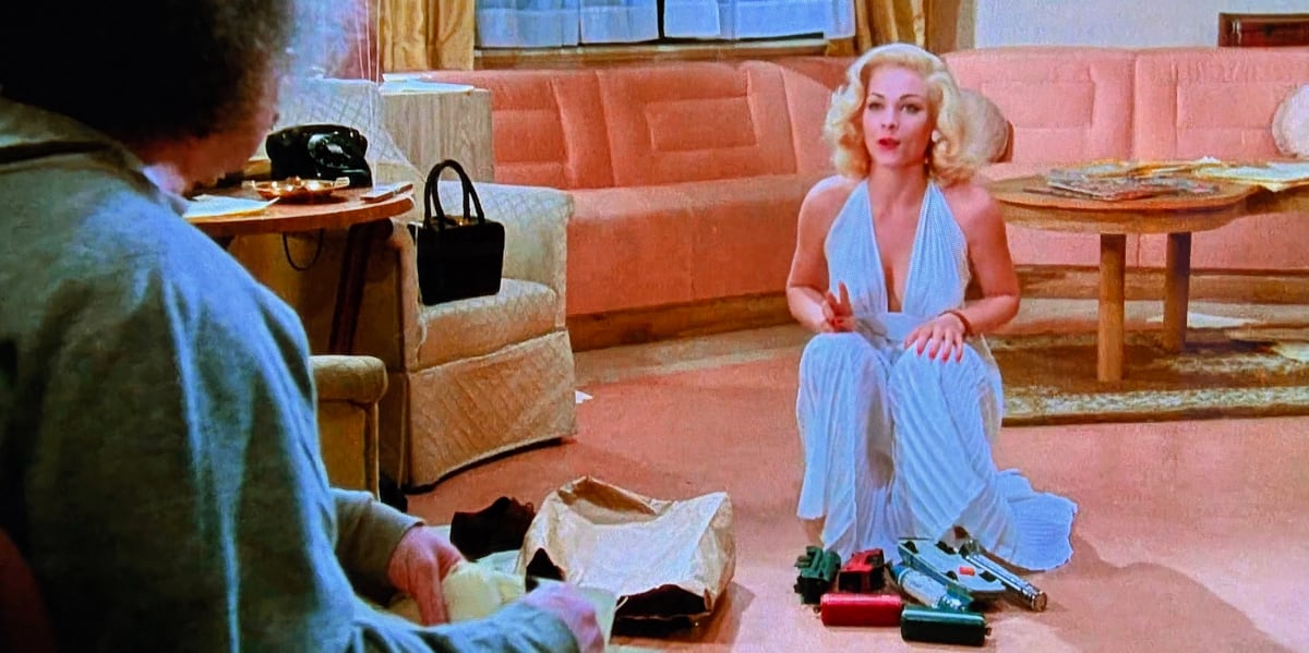 Marilyn Monroe kneeling with some childrens toys in a hotel room looking at Albert Einstein