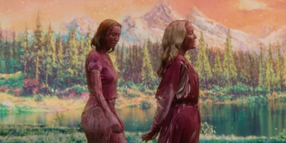 Two women covered in blood walk happily hand in hand.